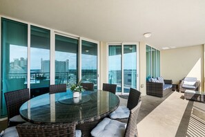 A balcony with a round glass table, wicker chairs, and a sofa. - 10% off 3-7 nights thru Dec. Ocean Drive. Oceanfront with OCEAN VIEW (from side). (North Myrtle Beach)