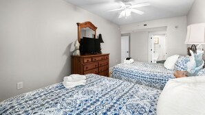 A bedroom with two beds, a dresser, a ceiling fan, and a mirror. - Ocean Drive. 3 bedroom 3 bath condo with an OCEAN VIEW (from side). Sleeps 10. (North Myrtle Beach)