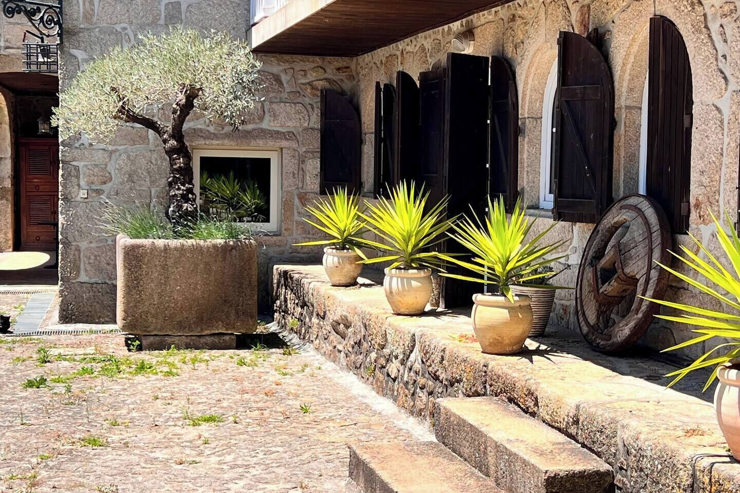 Un bâtiment en pierre doté d’un balcon en bois, de plantes en pot et d’un escalier en pierre.