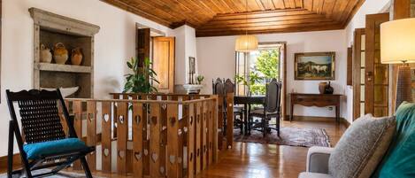 A cozy living room with a wooden ceiling, a dining area with a table and chairs, and a sofa with a cushion.