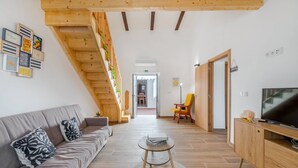 Ein modernes Wohnzimmer mit einer Couch, einem Fernseher und einer Treppe mit Pflanzen.