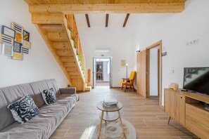 Ein modernes Wohnzimmer mit einer Couch, einem Fernseher und einer Treppe mit Pflanzen.