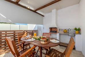 A wooden dining table set for a meal with a brick oven and a small kitchen area in the background. - A Casinha do Limoeiro (Faro)