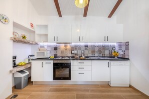 A modern kitchen with white cabinets, a microwave, a stove, and a dishwasher. - A Casinha do Limoeiro (Faro)