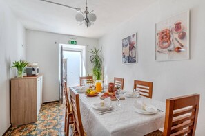 Ein Essbereich mit Tisch für vier Personen, einer auf einem Schrank stehenden Mikrowelle und einer Tür zu einem anderen Raum.
