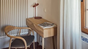 Una habitación con un escritorio de madera, una silla, un radiador y una cortina.