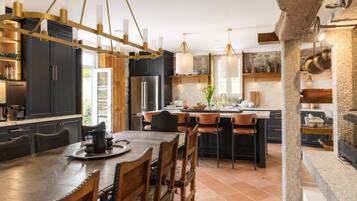 Une cuisine moderne avec des meubles de couleur sombre, un îlot central et des luminaires suspendus.