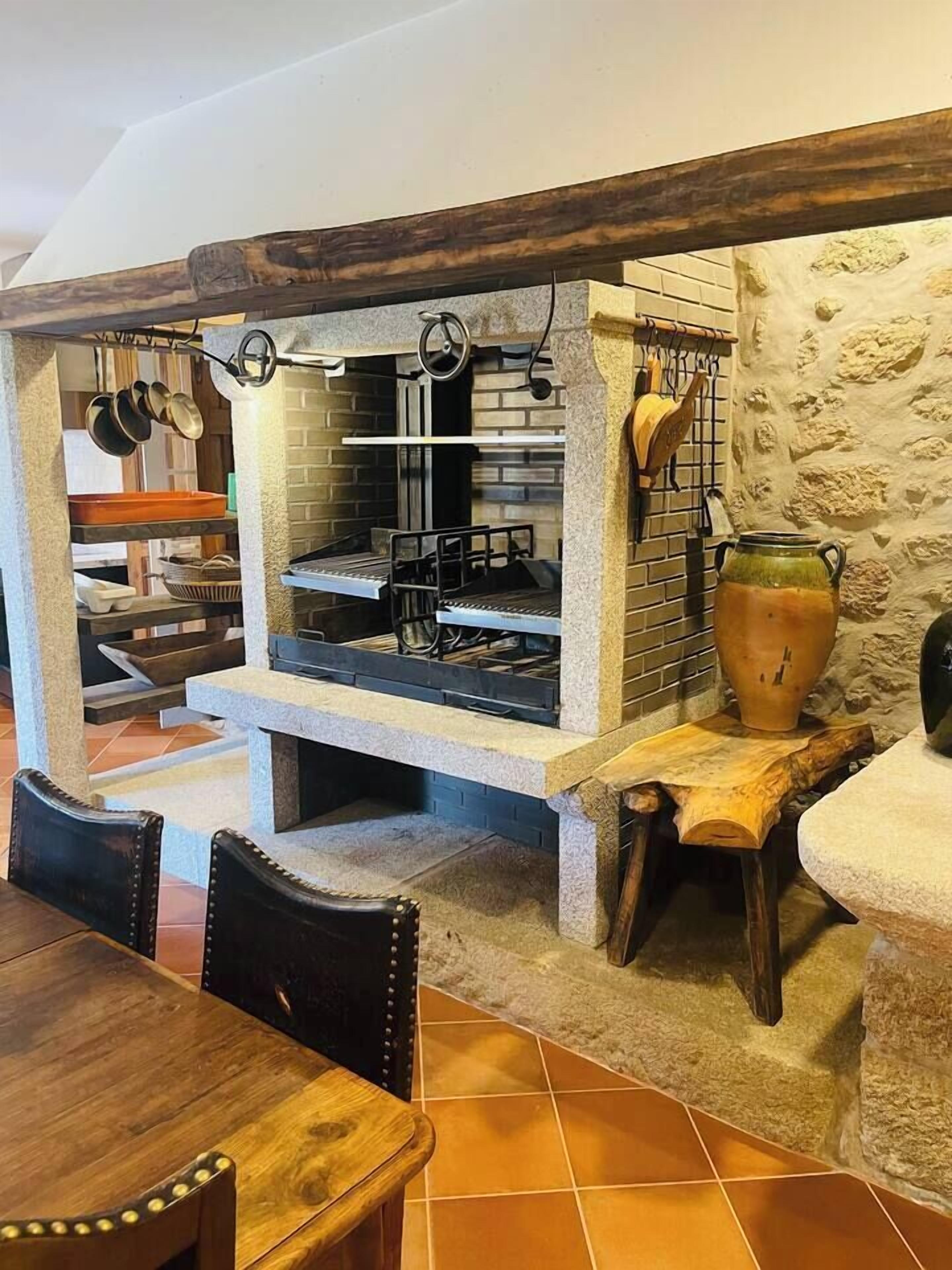 A rustic kitchen with a brick wall, wooden beams, and a stone countertop.