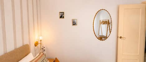 Une chambre à coucher avec un lit, une lampe de chevet, un miroir et une porte.