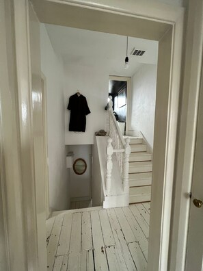A staircase leading to a second floor with a white railing and a hanging light fixture. - Bright, Calm and Trendy 2 Bedroom West London Flat (London)