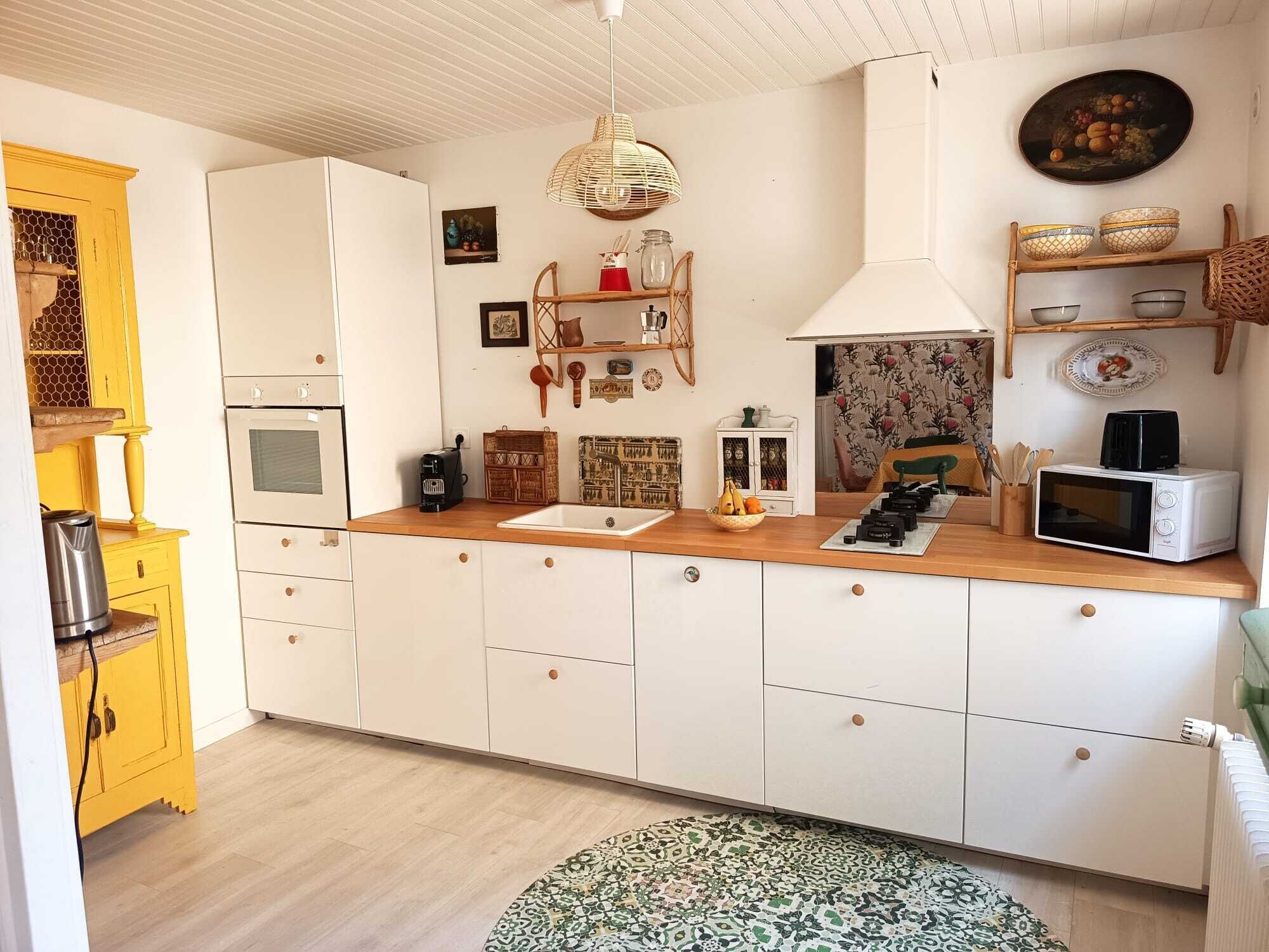 A kitchen with white cabinets, a wooden countertop, a hanging light fixture, and a microwave.