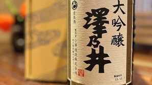 A bottle of Japanese sake with a label, placed on a wooden surface. - ARASAWAYA RYOKAN (Okutama)