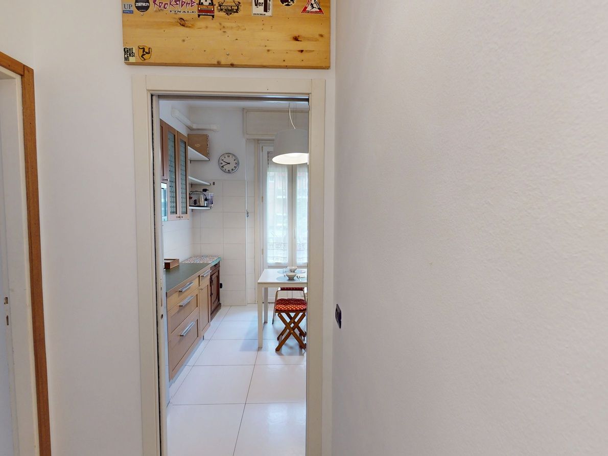 Un pasillo que conduce a una cocina con armarios, una mesa de comedor y una silla.