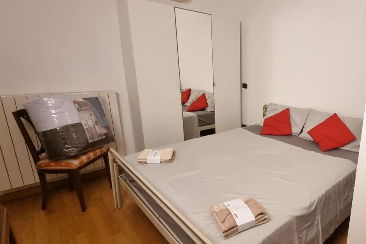 A hotel room with a bed, a chair, a desk, and a wardrobe.