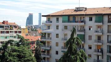 Un edificio residencial de varios pisos con balcones, cielo despejado y un rascacielos moderno a lo lejos.