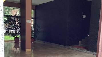 Un'ampia area interna con pavimento piastrellato, una pianta in vaso e una scala che conduce a un livello superiore.