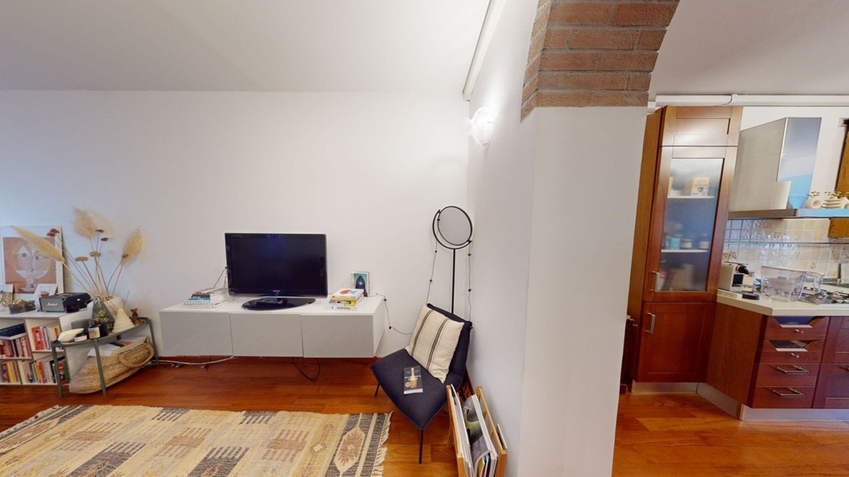 Sala de estar com televisão de tela plana, estante de livros e mesa de centro.
