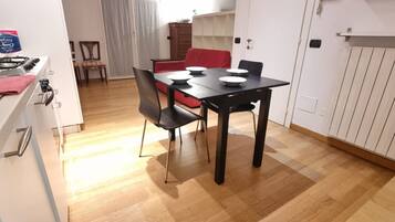 Una cocina compacta con una mesa de comedor, sillas y un sofá rojo al fondo.