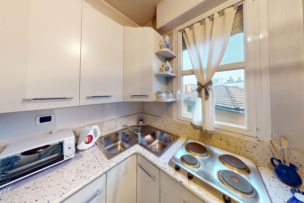 A kitchen with white cabinets, a built-in oven, a sink, and a stove.