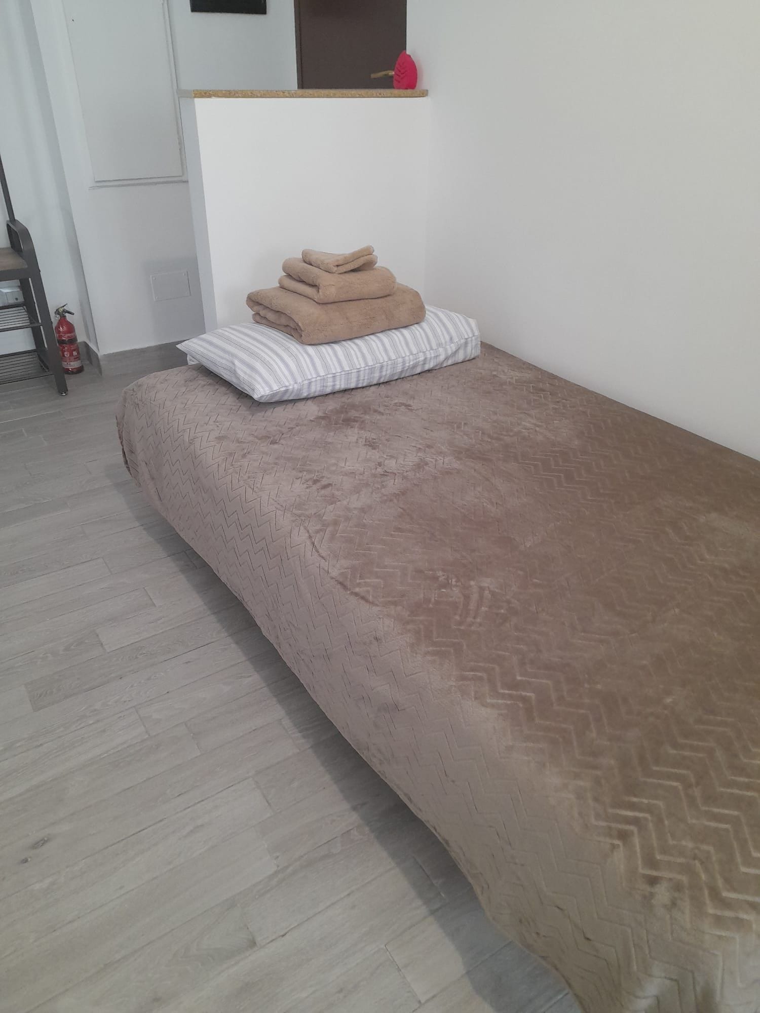 Una cama individual con una colcha estampada y un edredón doblado encima.