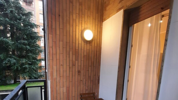 A balcony with a wooden wall, a table, and a chair. - Come a Casa Tua Milano (Milano)