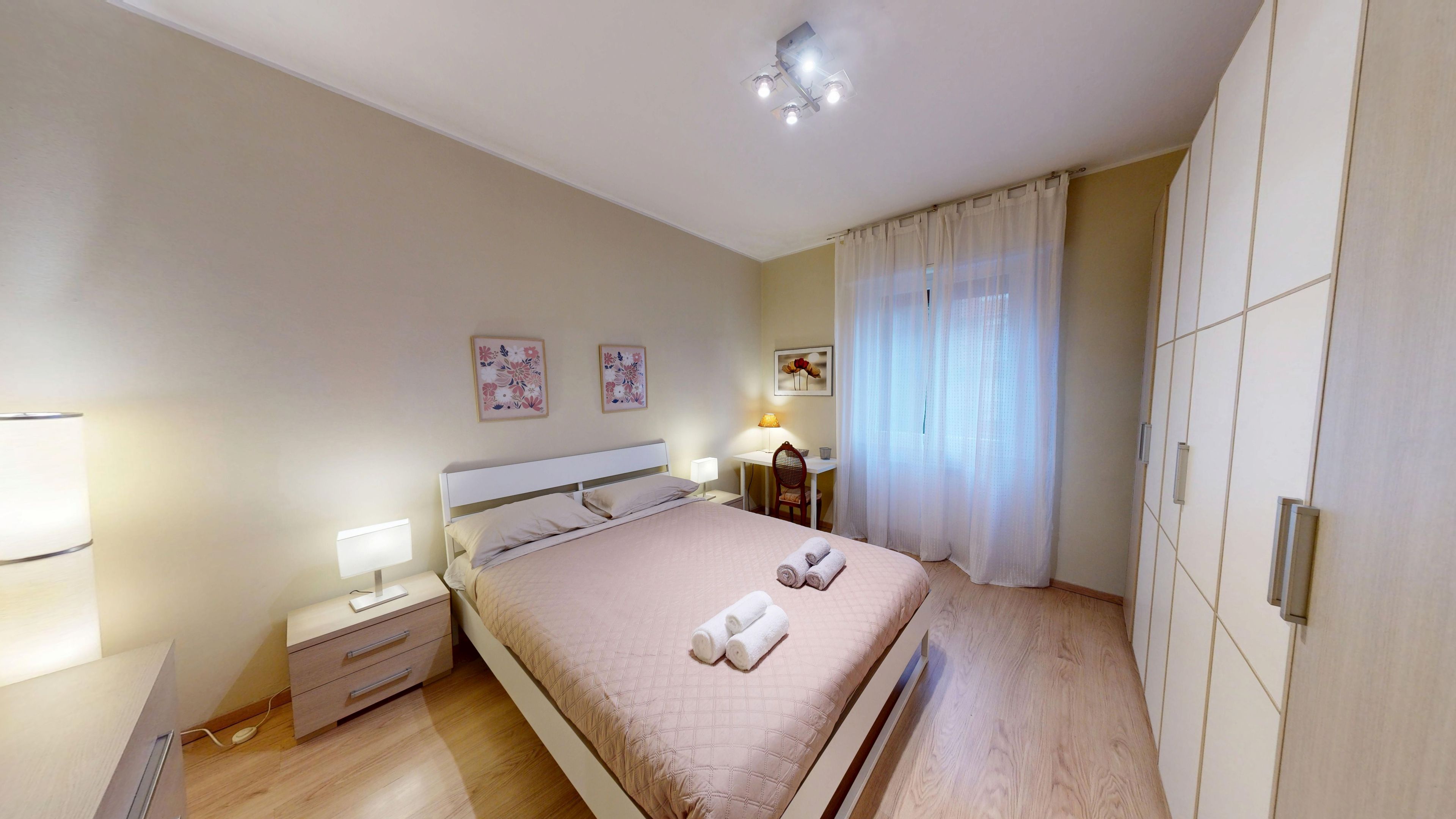 A bedroom with a bed, bedside table, lamp, and a wardrobe.