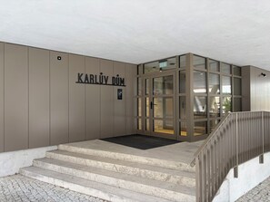 A modern entrance with a sign reading 'KARLIV DUM' and a set of concrete steps leading up to a glass door.