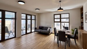A modern interior with a dining area, a sofa, and large windows.