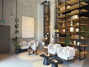 Eine moderne Lounge-Ecke mit Sofas, einem Couchtisch und einem Bücherregal voller Dekoartikel.