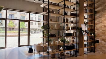 A modern interior with a large window, a central seating area, and a multi-tiered shelving unit filled with decorative items.
