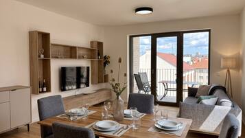 A modern living room with a dining area, large windows, and a view of the city.