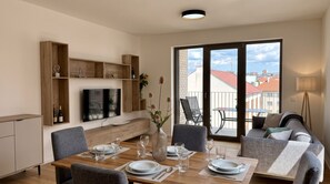 Ein modernes Wohnzimmer mit Essbereich, großen Fenstern und Blick auf die Stadt.