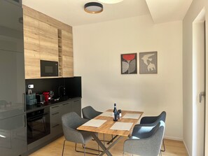A modern kitchen with a built-in microwave, a coffee machine, and a sink. There is a dining table with four chairs and two framed artworks on the wall. - Pekárenský Dvůr  (Jihomoravský kraj)