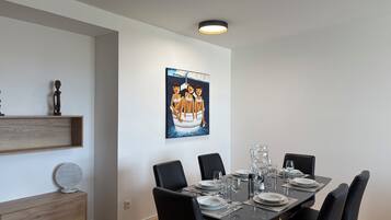 Comedor con una mesa rectangular dispuesta para seis comensales, sillas negras y un cuadro colgado en la pared.