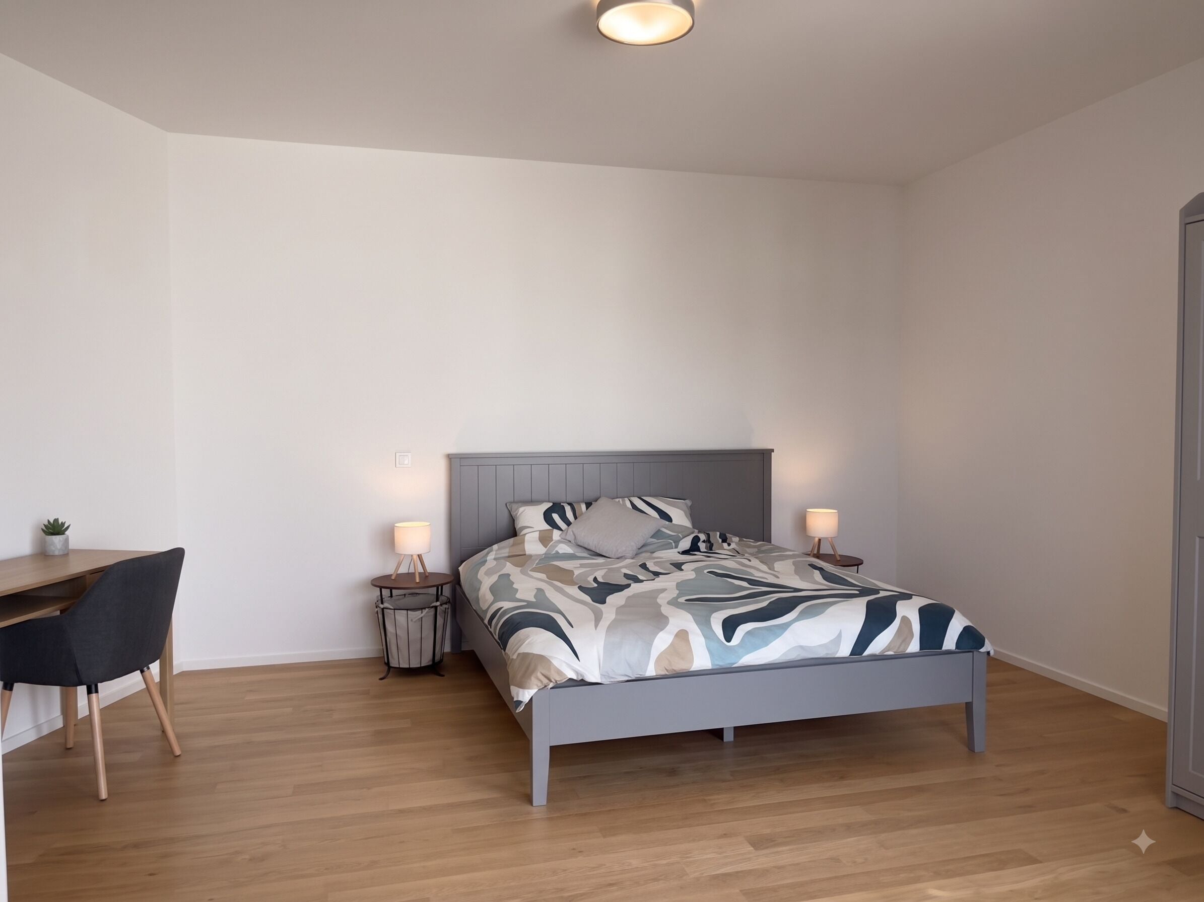 A bedroom with a bed, bedside tables, a desk, and a chair.