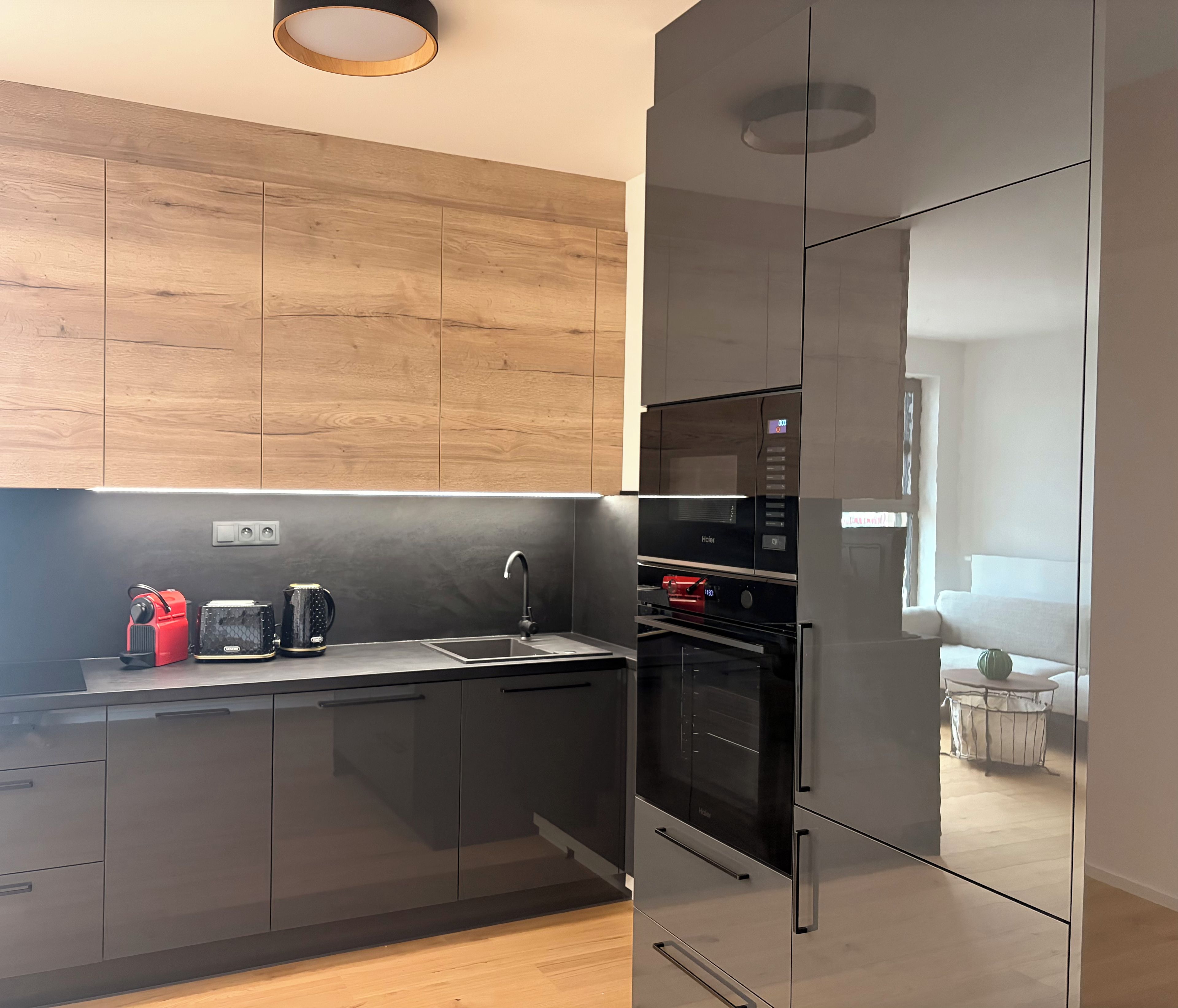 A modern kitchen with a wooden wall, stainless steel appliances, and a glass backsplash.