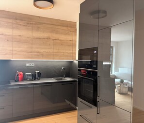 A modern kitchen with a wooden wall, stainless steel appliances, and a glass backsplash.