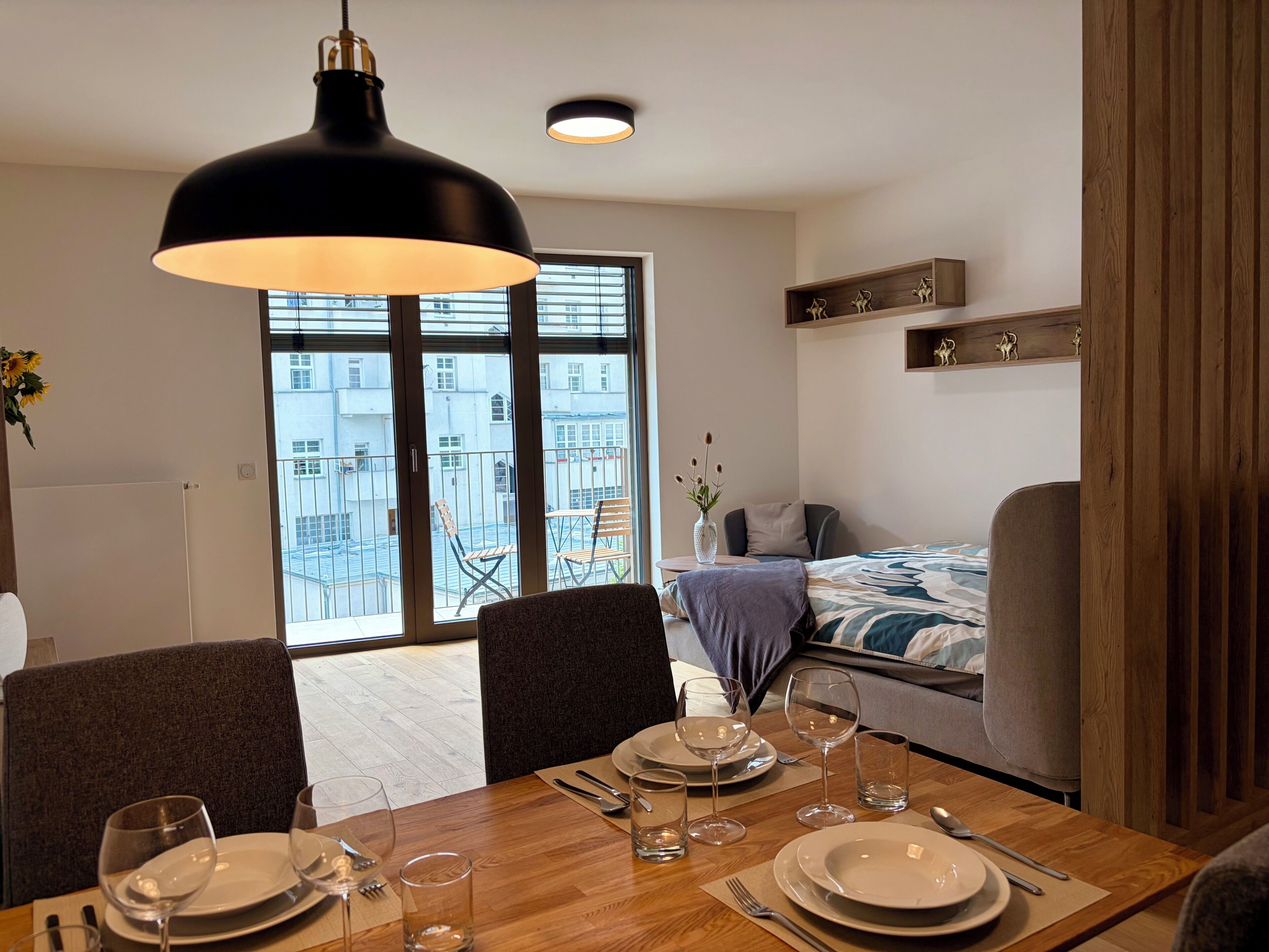 En matplats med ett bord dukat för fyra personer, en soffa och en säng i bakgrunden.