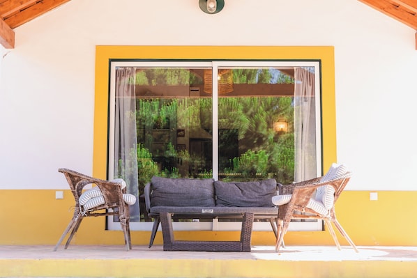 Un patio con mobiliario de mimbre y una puerta corrediza de vidrio.