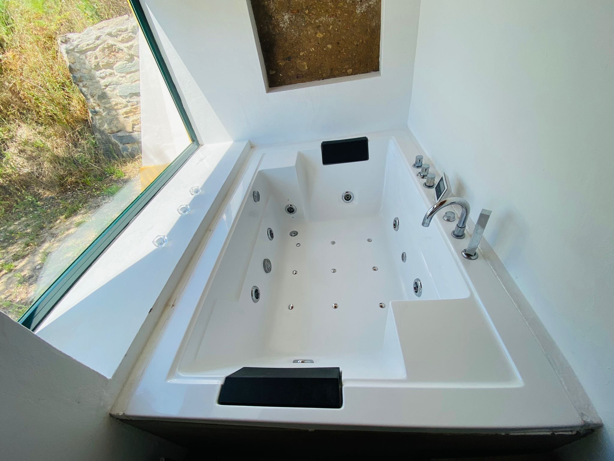 Un baño moderno con una bañera grande, una ventana y vistas al exterior.