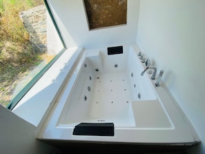 Un baño moderno con una bañera grande, una ventana y vistas al exterior.
