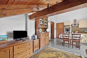 Eine Küche mit Holzausstattung, einem Esstisch für zwei Personen und einem Fernseher auf einem Holzschrank.