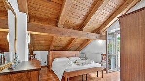 A bedroom with a wooden ceiling, a bed, a bedside table, and a window. - Alpine Loft Sommeiller (Bardonecchia)