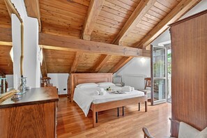 Ein Schlafzimmer mit Holzbalkendecke, einem Bett, einem Nachttisch und einem Fenster.