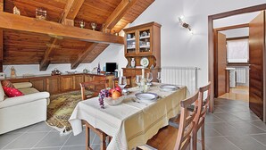 A dining area with a table set for four, wooden cabinets, and a cozy seating arrangement. - Alpine Loft Sommeiller (Bardonecchia)