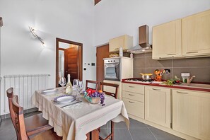 Eine kompakte Küche mit Essbereich, ausgestattet mit einem Backofen, einem Herd und verschiedenen Küchenutensilien.
