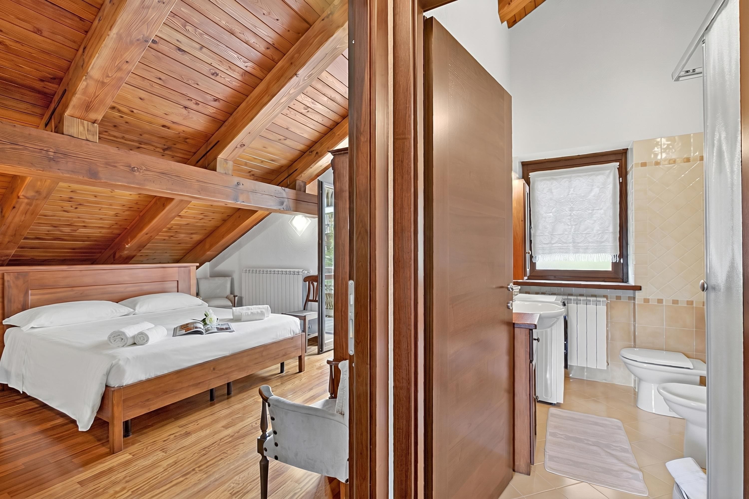 A bedroom with a wooden ceiling, a bed, and a chair.