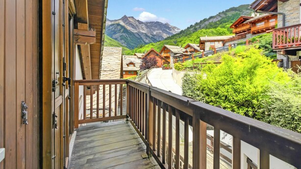 A wooden balcony with a view of a mountain village. - Alpine Loft Sommeiller (Bardonecchia)