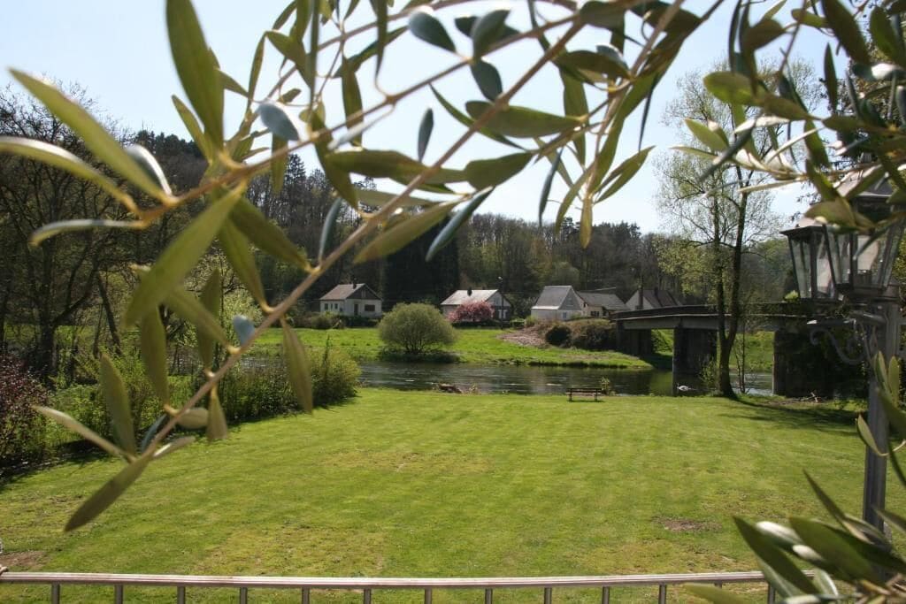 Un jardin bien entretenu, avec une pelouse, un petit étang et un pont.