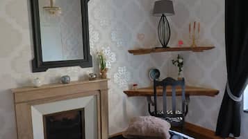 Ein Schlafzimmer mit Kamin, Spiegel, Lampe, Stuhl und Bett.